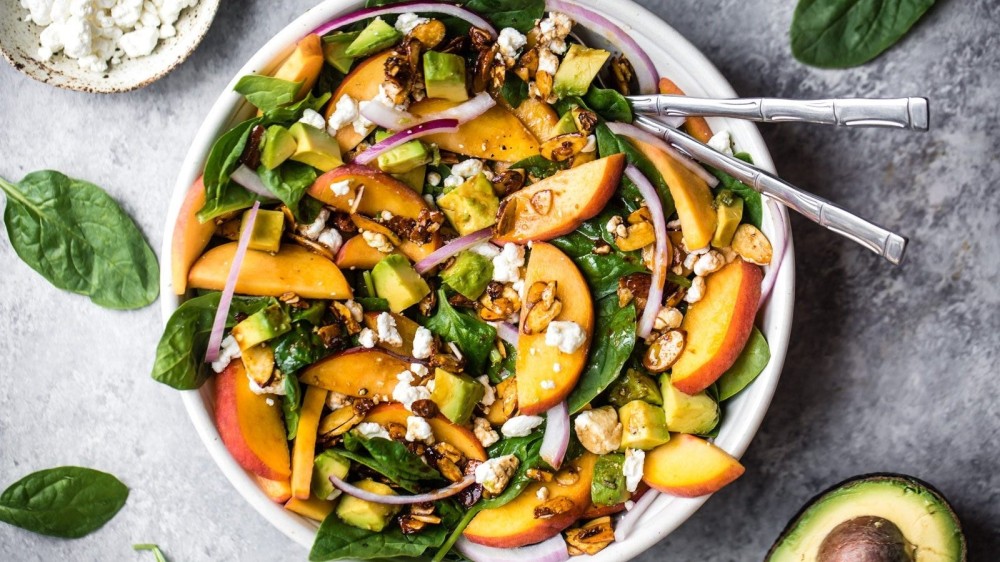 A gorgeous summer spinach salad toppe dwith peach slices, creamy goat cheese, toasty almonds, avocado and redo onion.