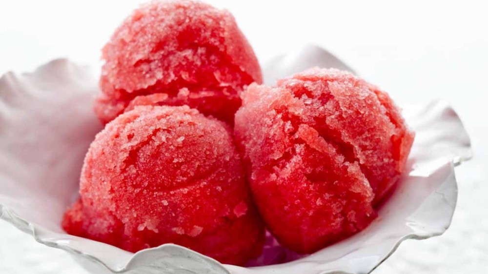 Three scoops of watermelon sorbet in a glass bowl. 