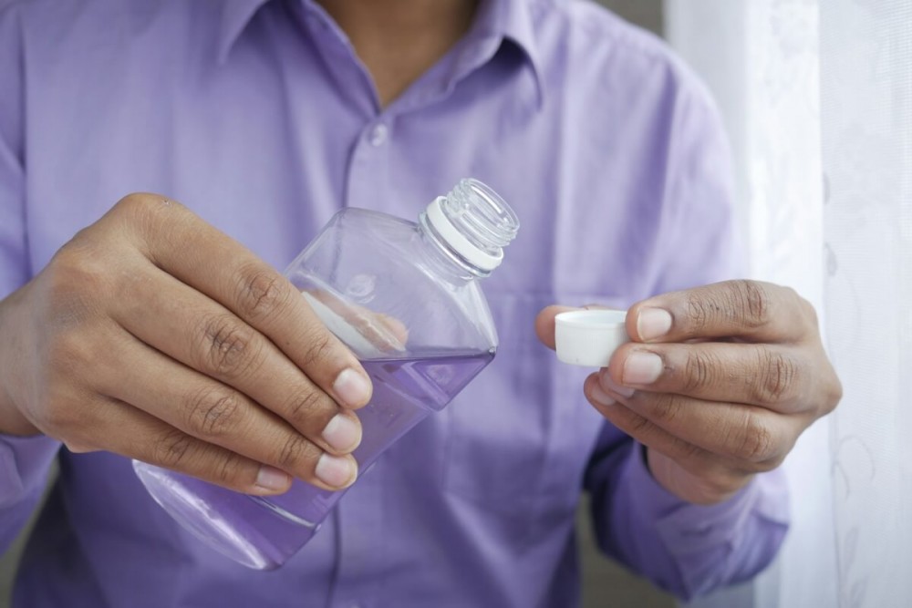 person holding white plastic bottle mouthwash