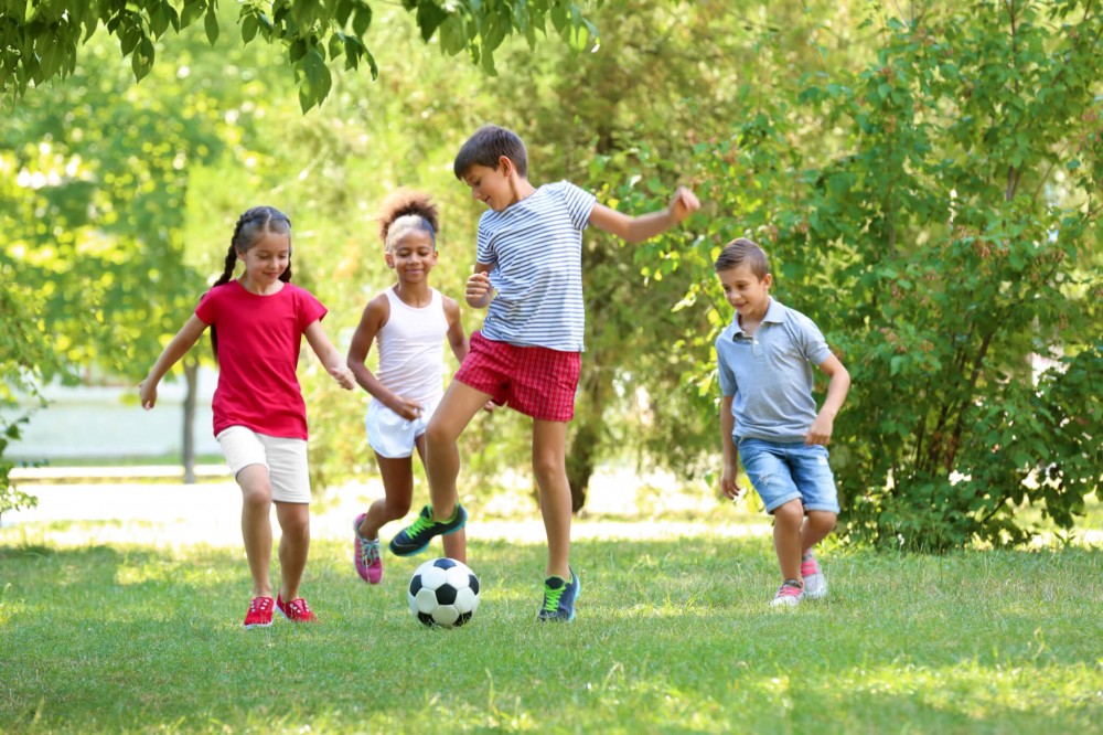 Children playing soccer outside in a park